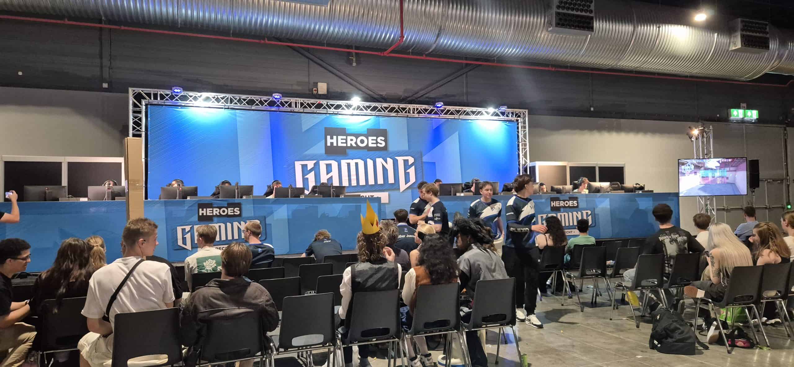 Gaming toernooi op podium met spelers achter schermen en publiek in de zaal